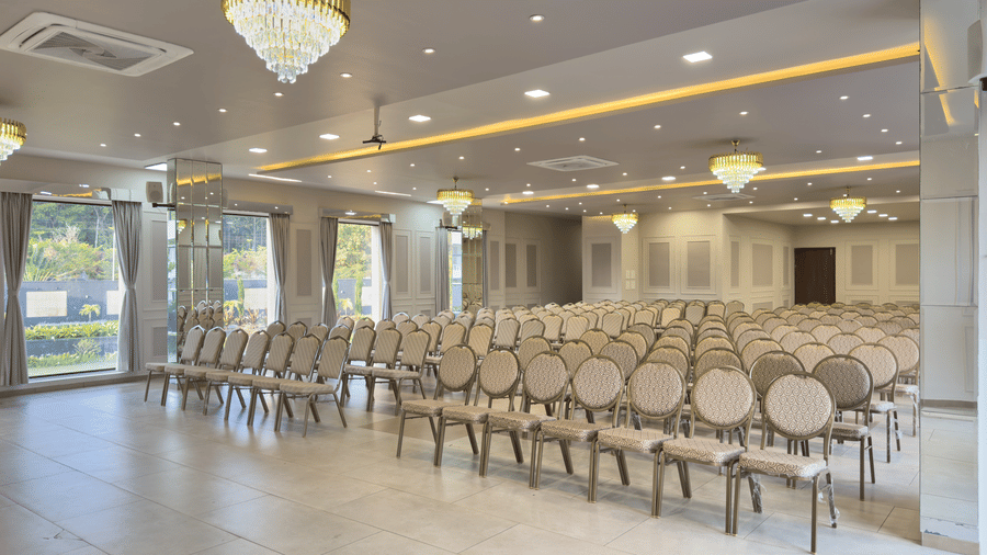 Large, modern hotel conference room set up theatre-style with rows of light-coloured chairs and elegant crystal chandeliers at Bindiga Peak Resorts.