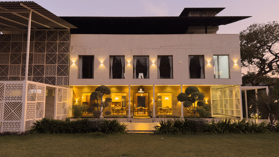Facade of a modern white two-storey building with glowing indoor lights and a dark sky above at Bindiga Peak Resort.