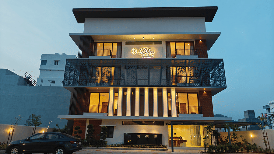 The multi-storey exterior of Bliss Giriya By Bergamont Tiruvannamalai illuminated at twilight with a paved forecourt.