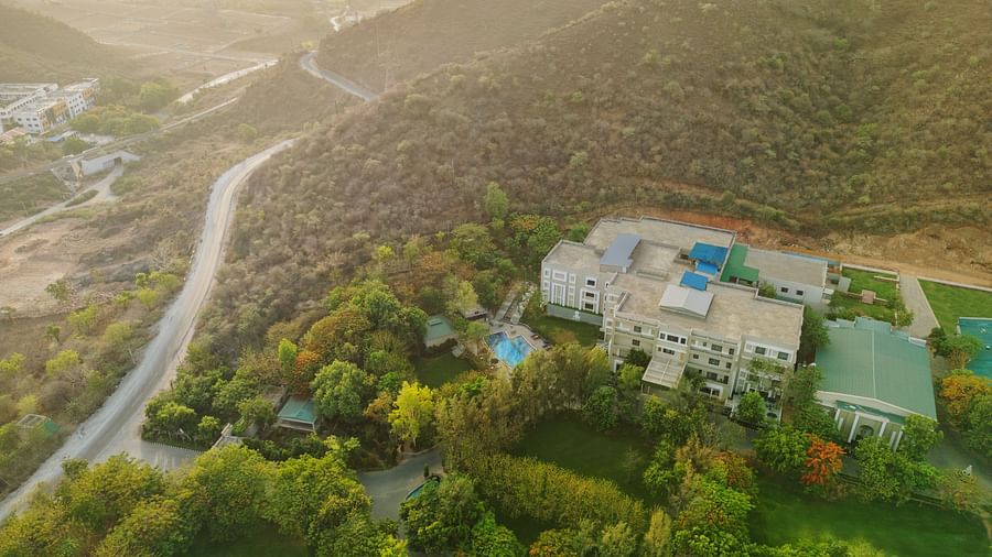 Aerial view of Essentia Luxury Resort & Spa, Udaipur with a small road and trees in view