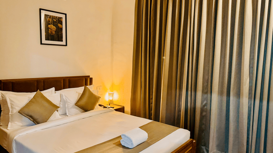 Diagonal view of the bedroom of Coral 4BHK showcasing its plush bedding, warm lighting, and closed curtains | Kove Smart Stays