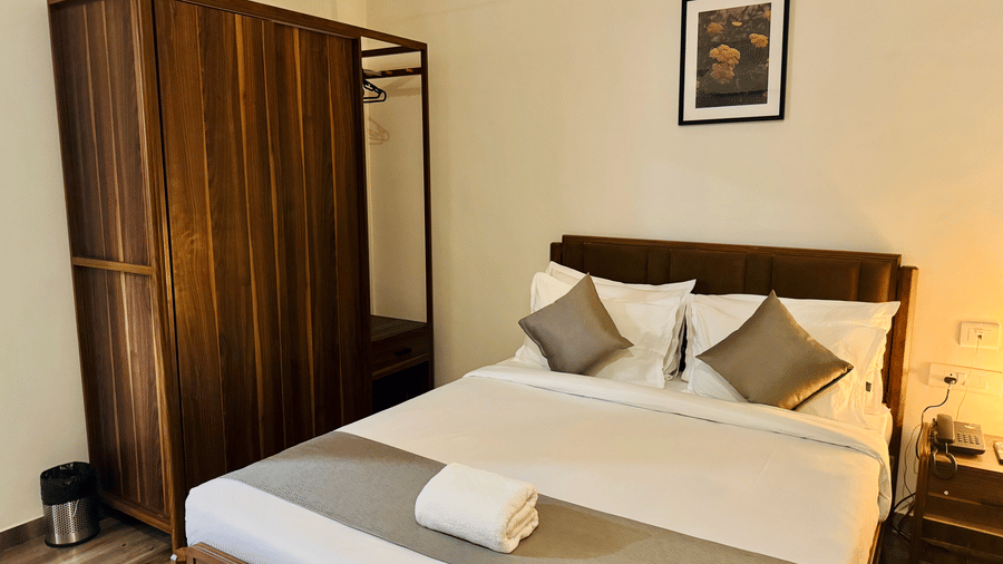 Furnishings including the queen size bed, a wooden wardrobe, and a bedside table seen in the bedroom of Coral 4BHK at Kove Smart Stays.