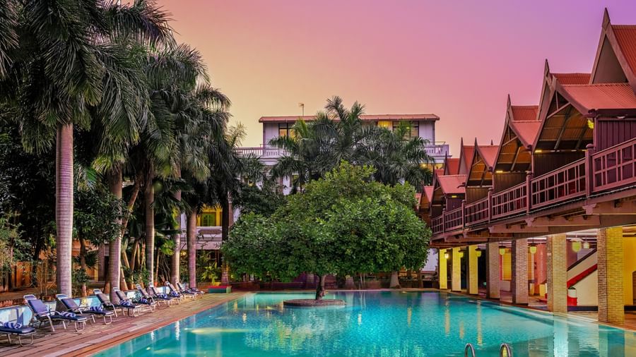 Resort swimming pool at dusk with colorful sky and traditional architecture | Mango Hill, Pondicherry