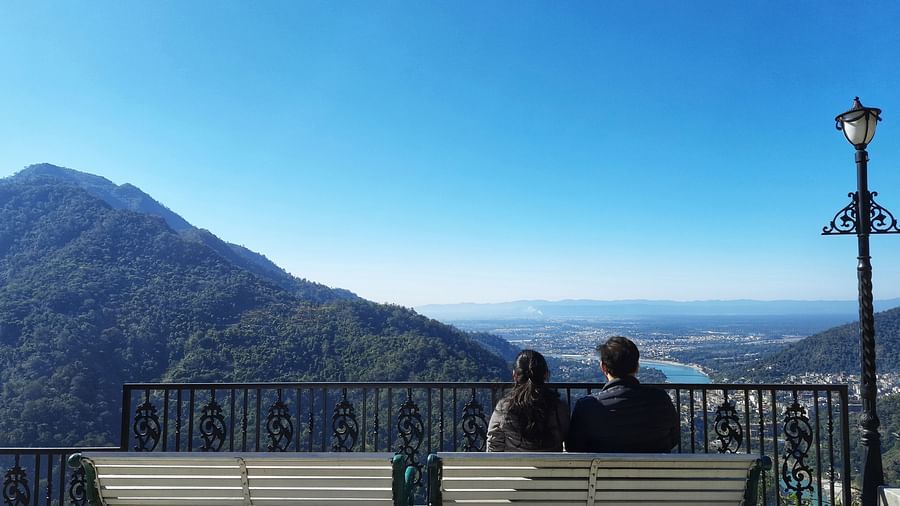 a couple sitting on a bench looking at the mountain and valley below - neer ganga Resorts