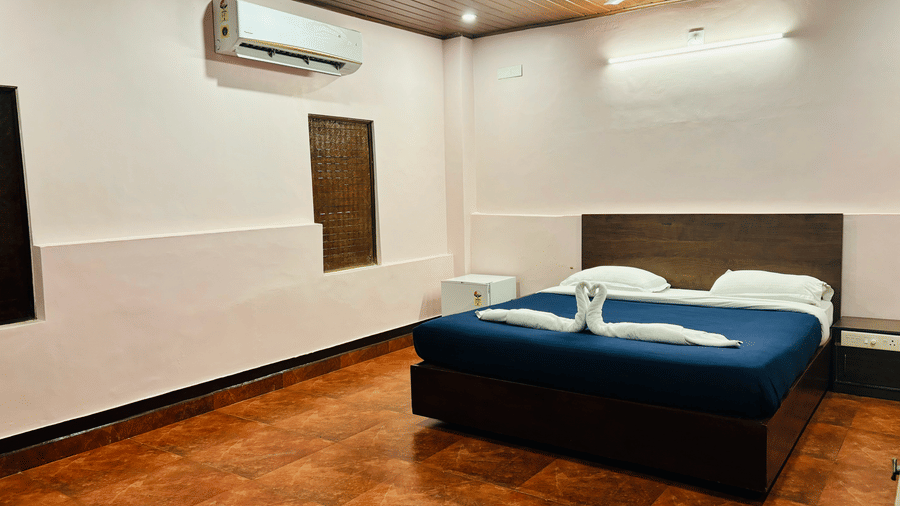 Spacious bedroom with queen bed, ceiling fan, and air-conditioning at Paradise Lagoon Resort, Udupi.