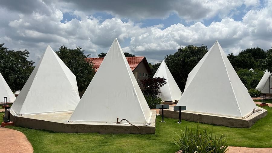 A scenic view of a resort area with tents lined along a neat walkway, surrounded by a well-maintained lawn.