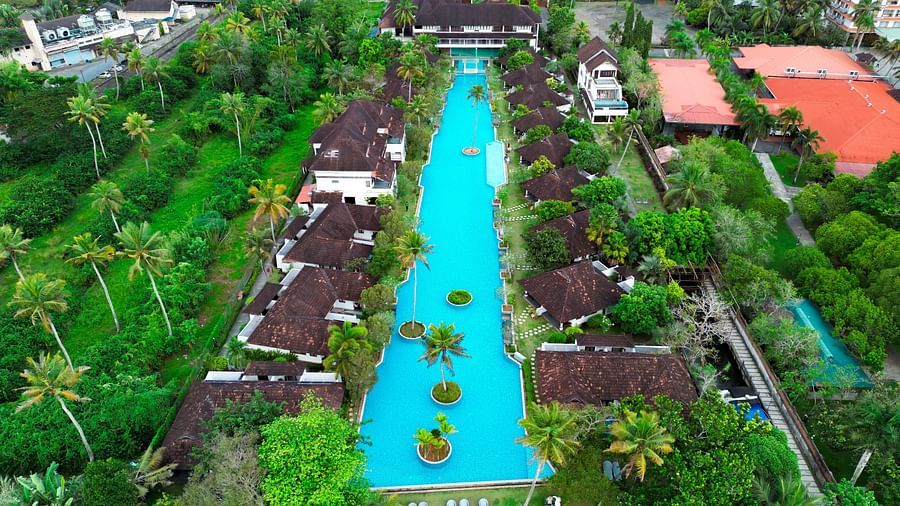 an image of an aerial view of a swimming pool with rooms and trees - Rhythm Kumarakom