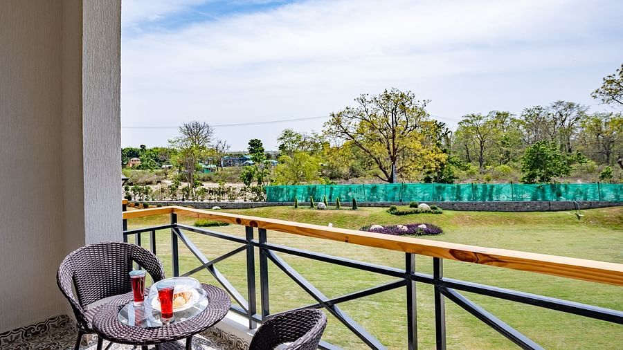 A balcony in the river view room with comfortable chairs placed around a coffee table for relxation - Shervani Pebbles & Pines, Corbett