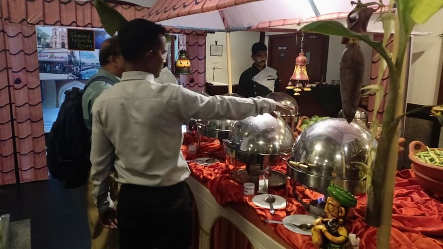 Man behind a table of food at SRM Hotel Tiruchirappalli- Hotel 