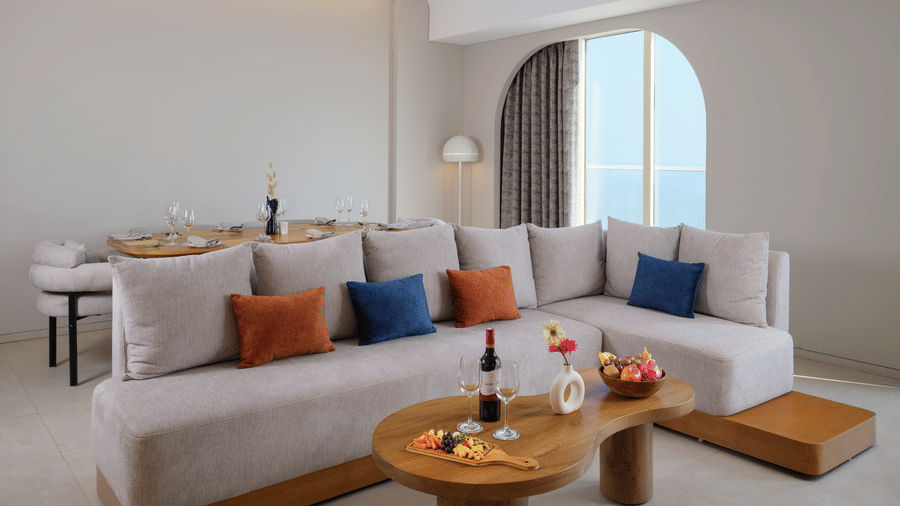 The Intimate Escape Suite living room at Swosti Premium Beach Resorts, Puri, with sofas, a table, and a large window..