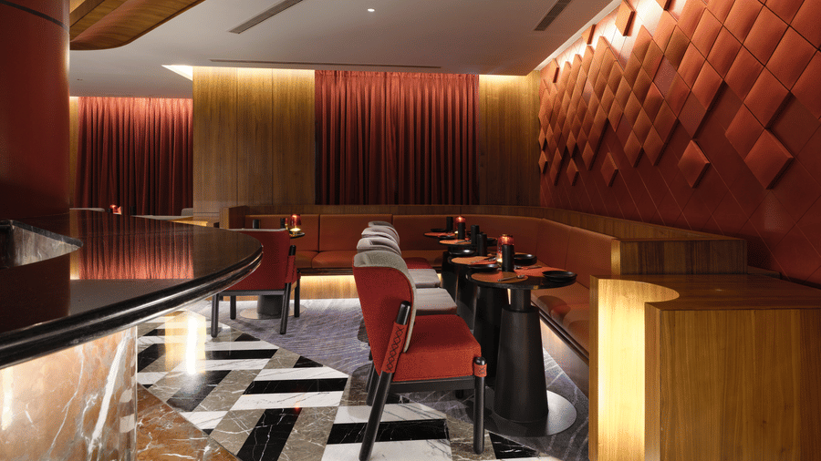 The well-lit bar of Swosti Premium, Bhubaneswar, with chairs, and tables arranged on a checkered floor. 