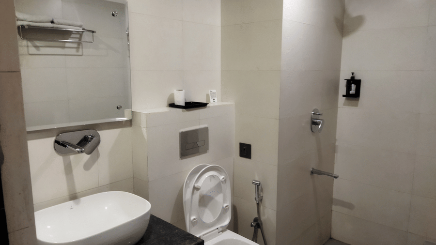 En-suite bathroom at TGI Apple Inn, Ajmer Road, Jaipur, with a white counter-top basin, modern toilet and walk-in shower.