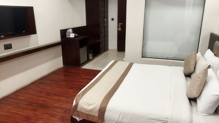 A modern hotel room with a large bed, a flat-screen TV, and wooden flooring - TGI Apple Inn, Jaipur 