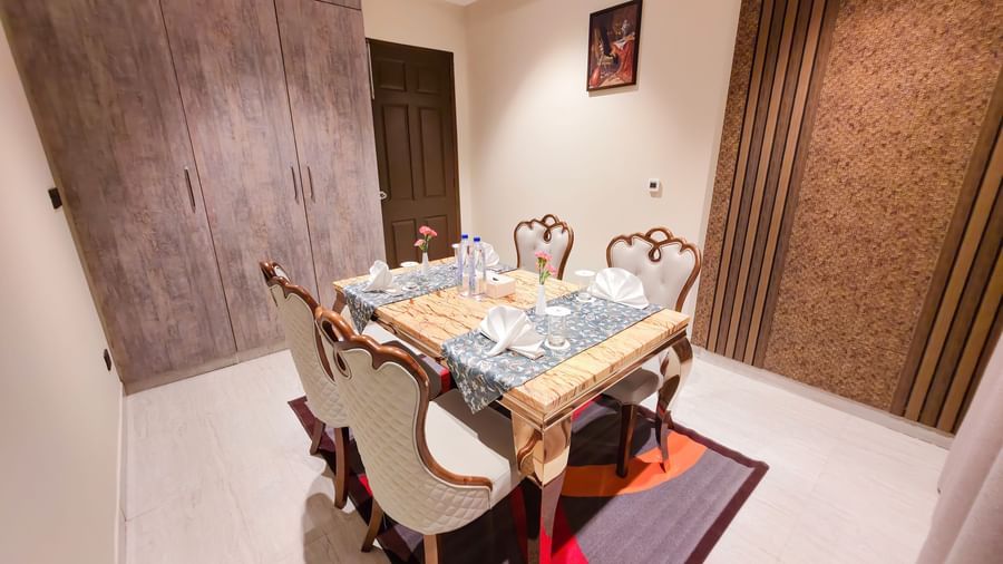 The dining area of the Presidential Suite featuring a well arranged dining table with cutlery and shiny glassware.