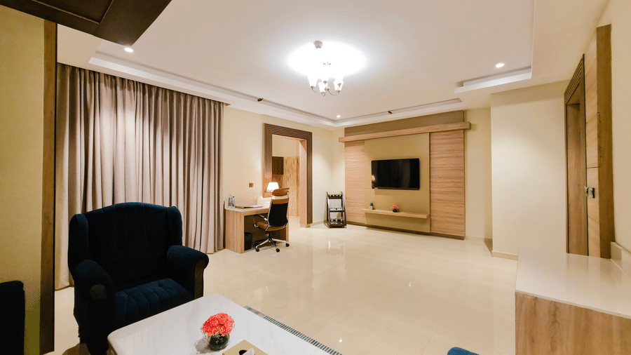 An expansive living area at the Empress Suite, a lavish accommodation in New Delhi, featuring a wall-mounted television at the far end of the room at The Meriton.