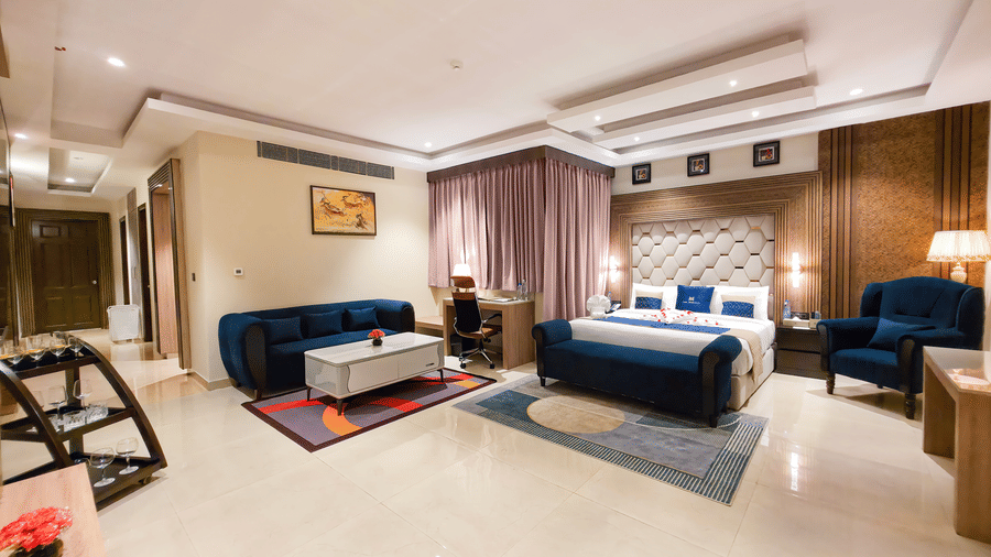 Full view of the Presidential Suite featuring the master bedroom along with a separate seating area in the corner at The Meriton | Stay in New Delhi