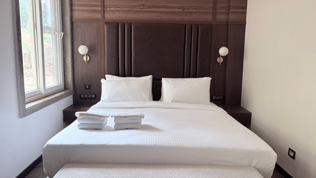 Clean, minimalist bed setup with plush white linens - Lords Riverside Resort, Muduba - Shivamogga