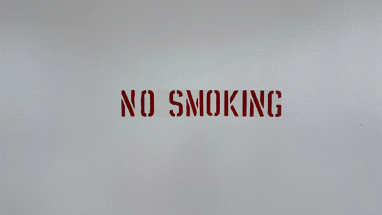 No smoking sign displayed on a plain wall.