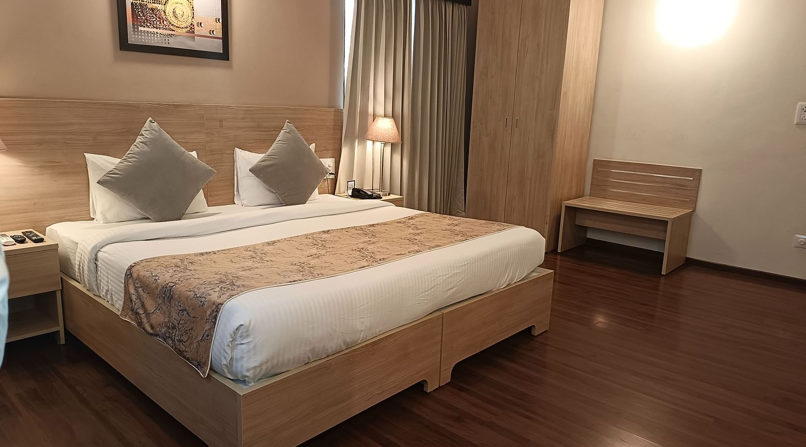 A double bed with a painting hung above inside Premium Studio at Starlit Suites, Shirdi