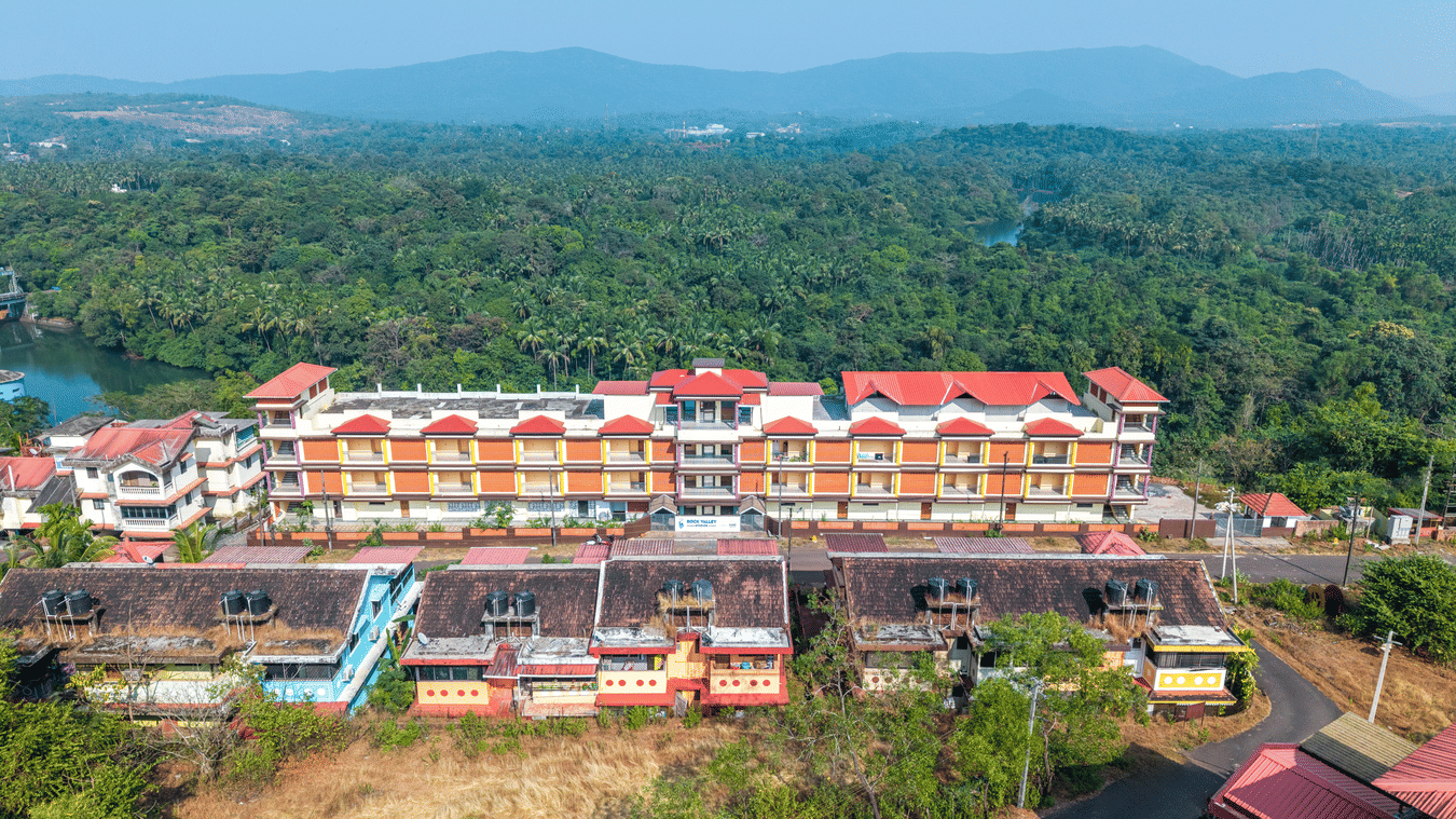 A high view of a large hotel complex with red roofs surrounded by forest.