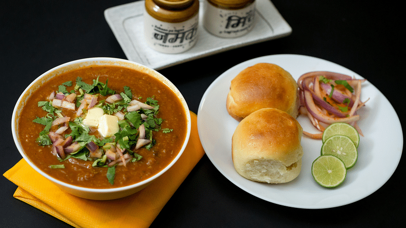 Toasted buns and masala curry topped with butter and onions