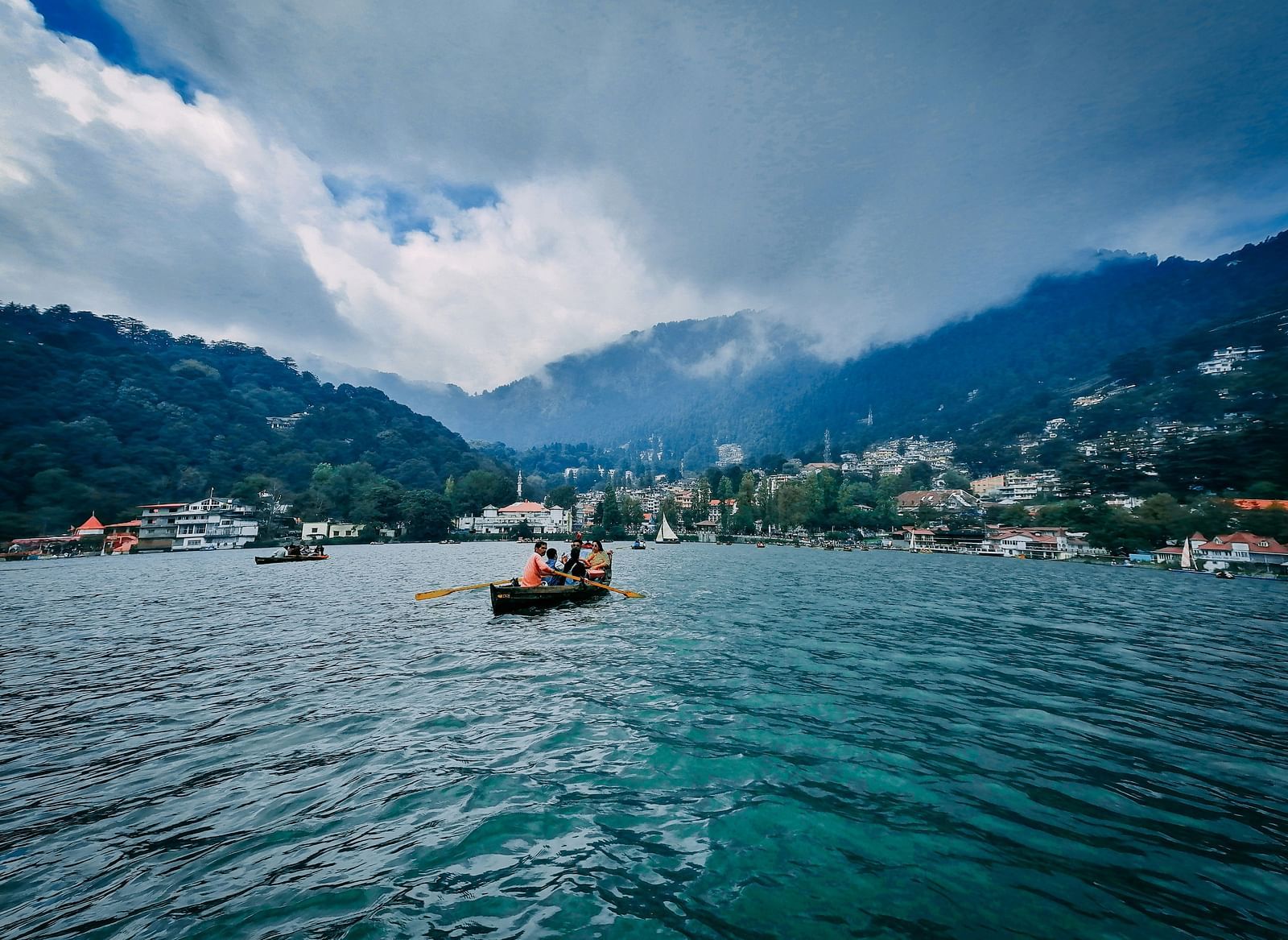 Boats on a serene lake with hills and town buildings in the background.