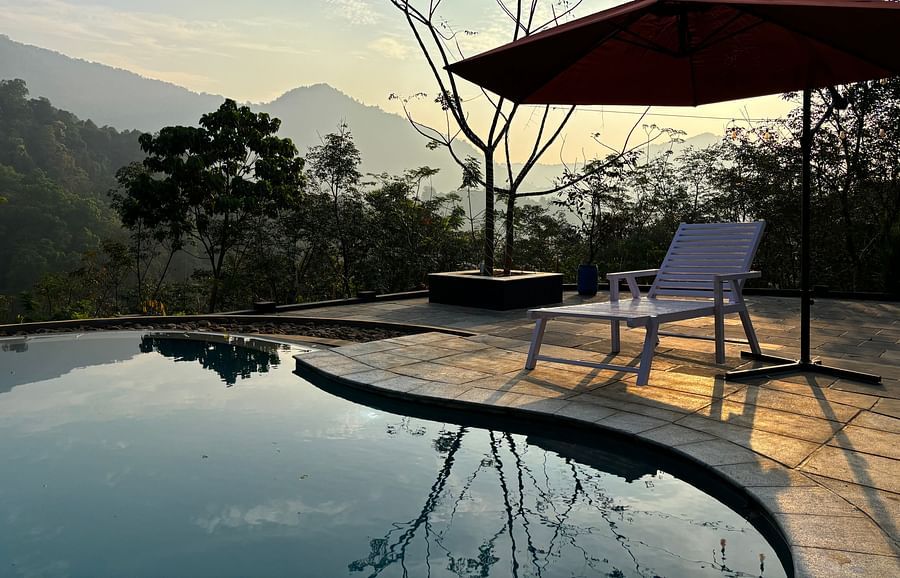 the swimming pool at Holistic Stay Eco Resort, Kannur featuring a sitout area overseeing the Brahmanagiri Mountains