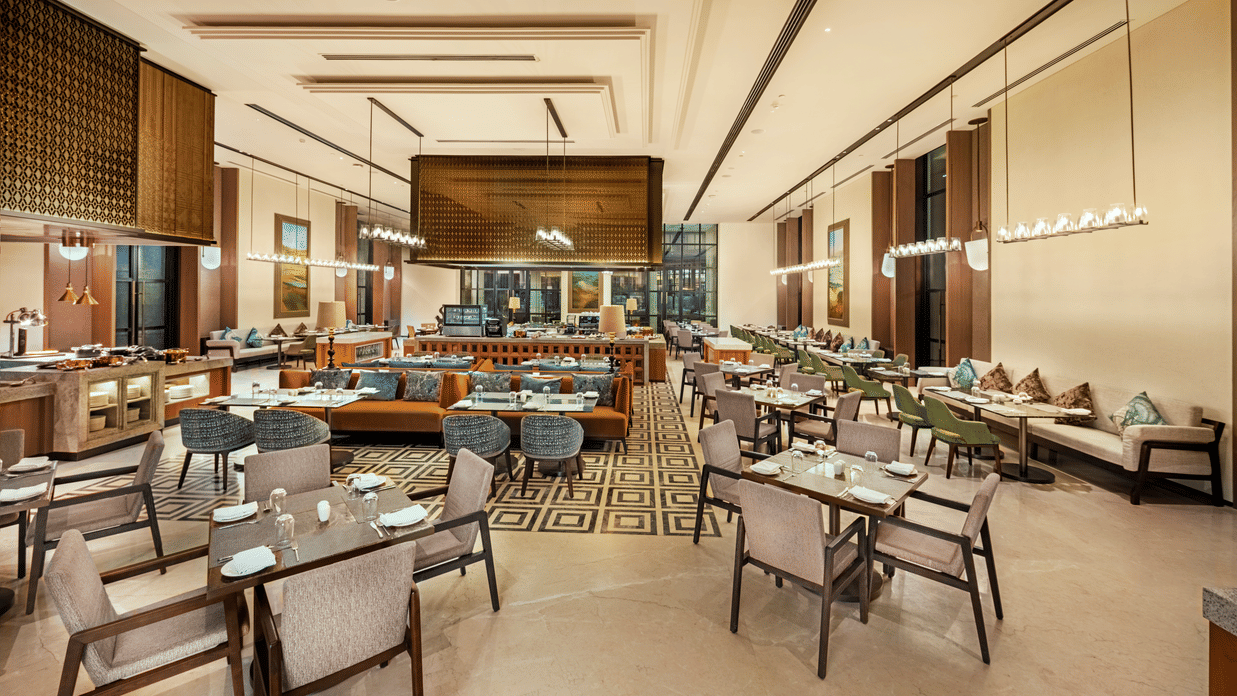 Wide view of CHITHIRAI restaurant at The Residency Signature Madurai with dining tables, wooden interiors, patterned flooring, and warm lighting.