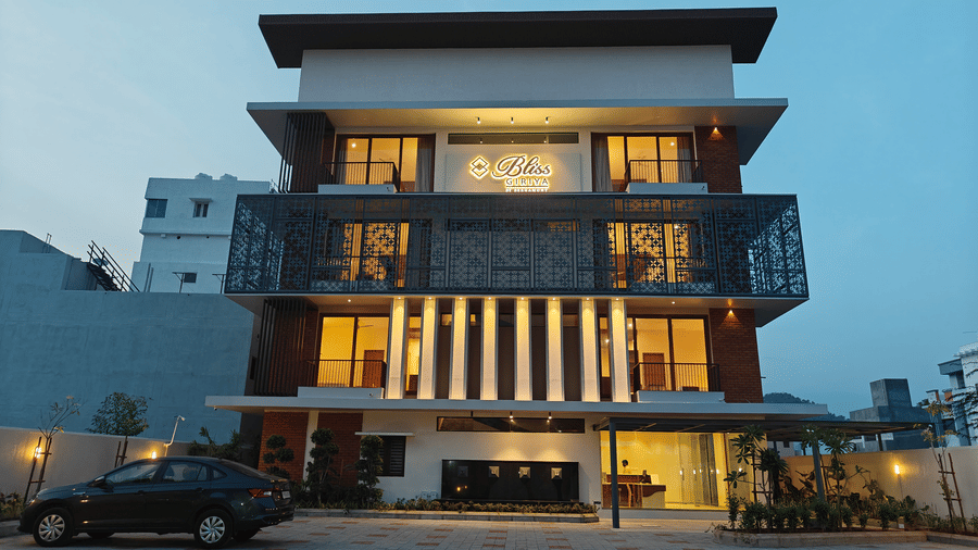 The multi-storey exterior of Bliss Giriya By Bergamont Tiruvannamalai illuminated at twilight with a paved forecourt.