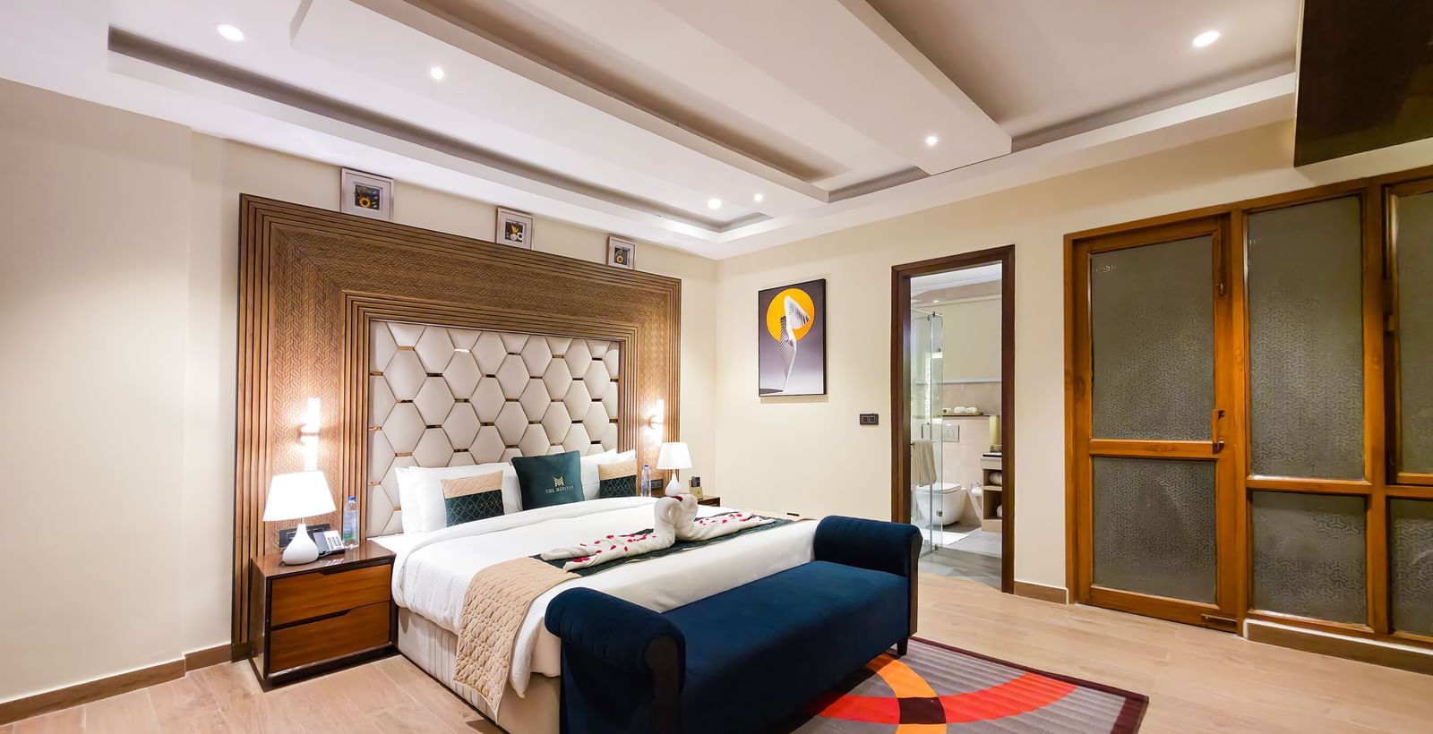 A wide angle shot of the bedroom at the Empress Suite featuring a plush double bed along with a rug on the floor in front of it at The Meriton.