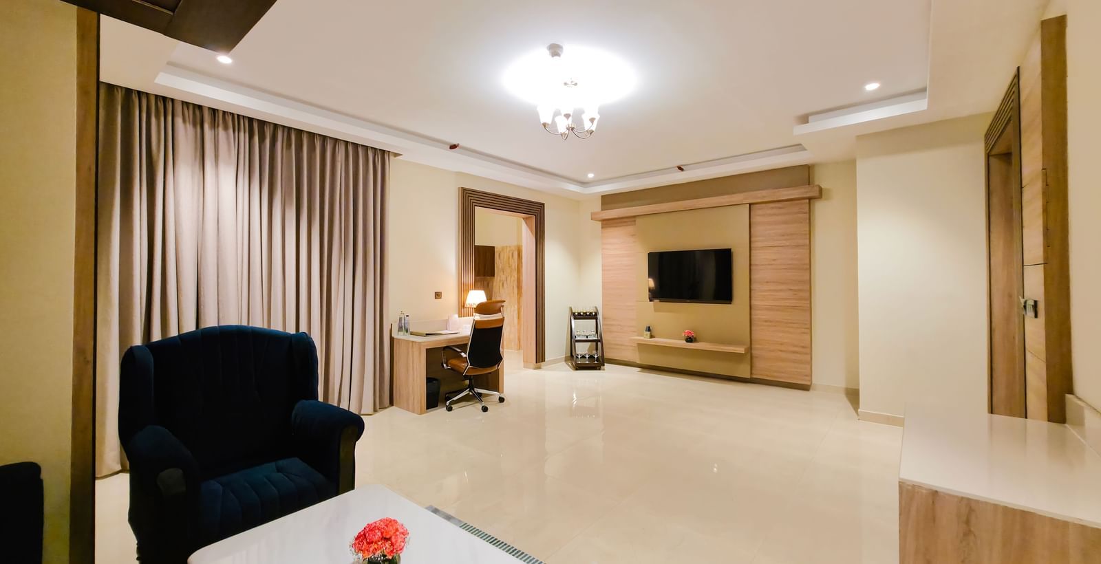 An expansive living area at the Empress Suite featuring a wall-mounted television at the far end of the room at The Meriton.