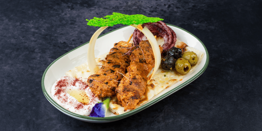 Tawook Chicken Skewers garnished with onions and olives at The Wild Fork restaurant in La Marvella, Bengaluru. 