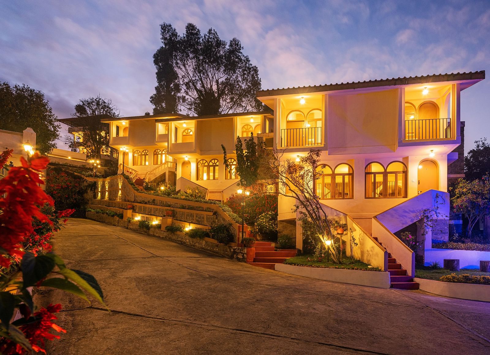 Resort entrance illuminated at night with warm lights, featuring a multi-story building and surrounding garden.