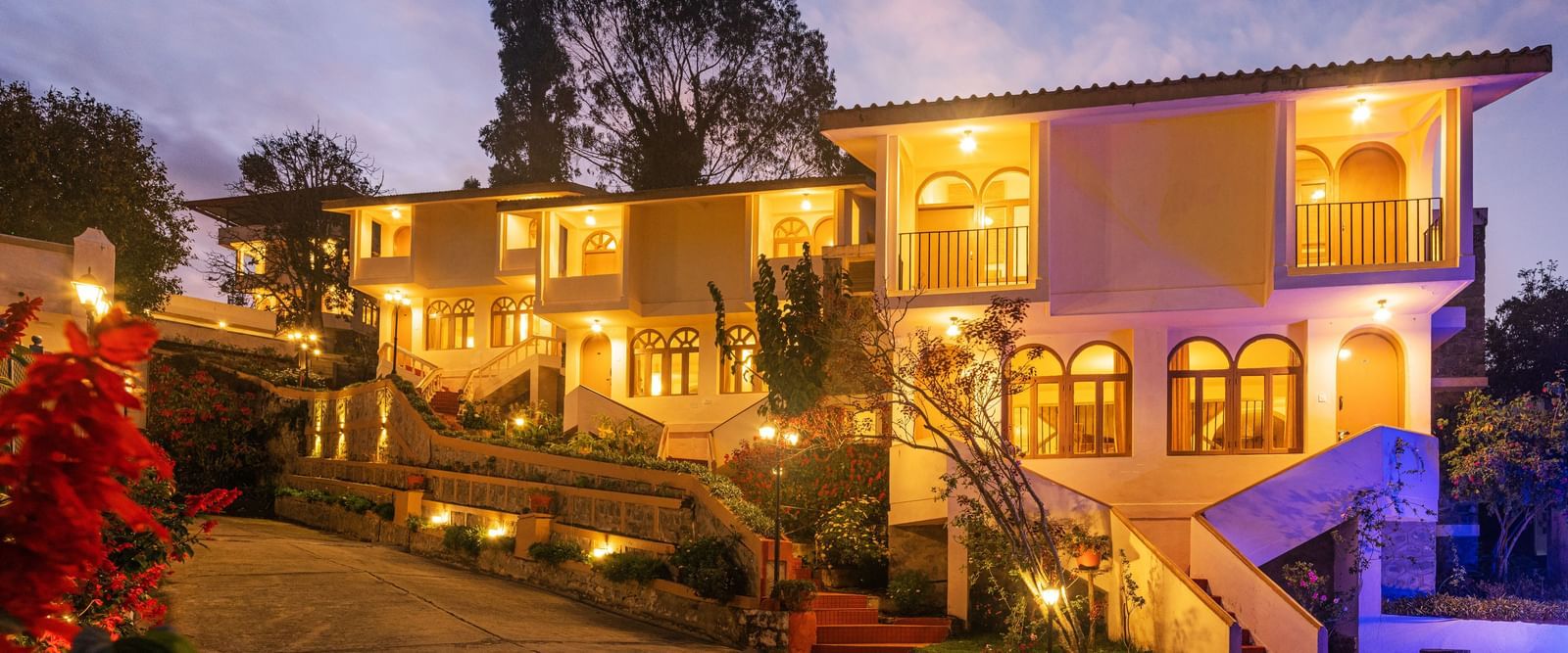 Resort entrance illuminated at night with warm lights, featuring a multi-story building and surrounding garden.