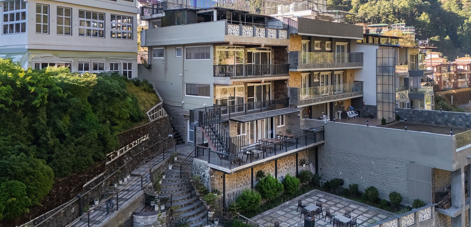 Exterior view of the hotel building with surrounding greenery and hillside landscape in the background.