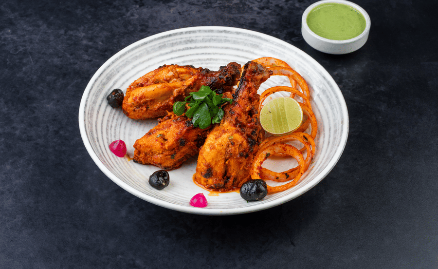 Tandoori Roast Bird served with spicy onion, lime, and a sauce at The Wild Fork restaurant in La Marvella, Bengaluru.