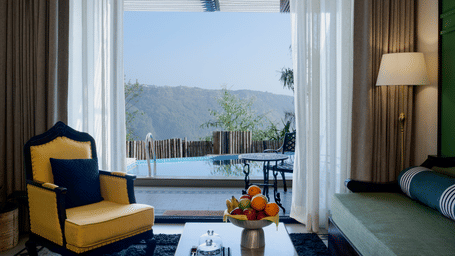 Waterfall Deck Pool Suite at Polo Resort Cherrapunji with yellow armchair, fruit bowl on coffee table, sheer drapes and private plunge pool view.