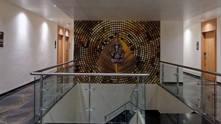 Corridor with glass railing and a poster on the wall Side view of twin beds with a television in font and ceiling on the wall at Ankit Hotel, Jabalpur