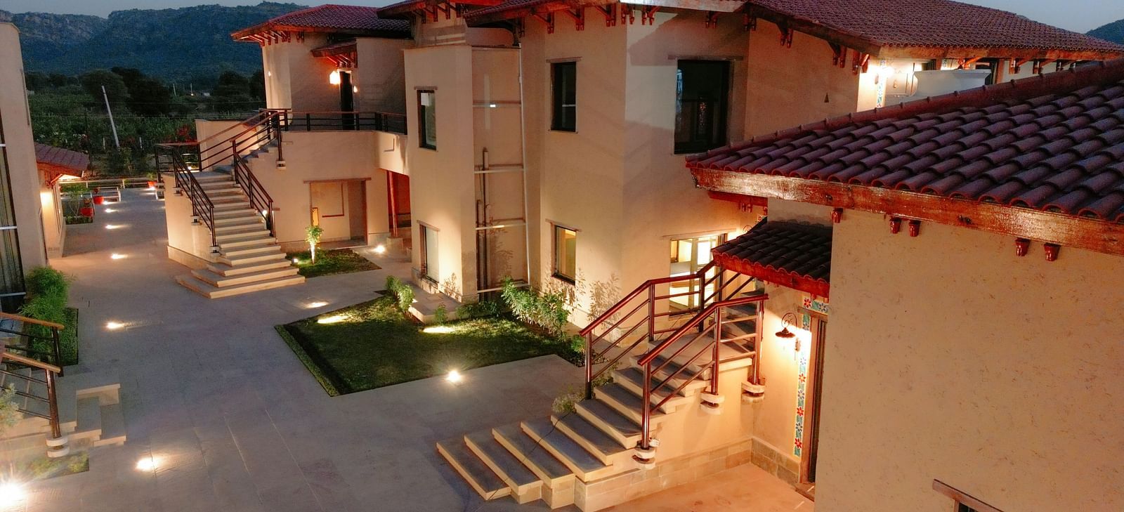 The resort buildings illuminated at dusk, showing pathways and outdoor lighting at Aamaghati Wildlife Resort.