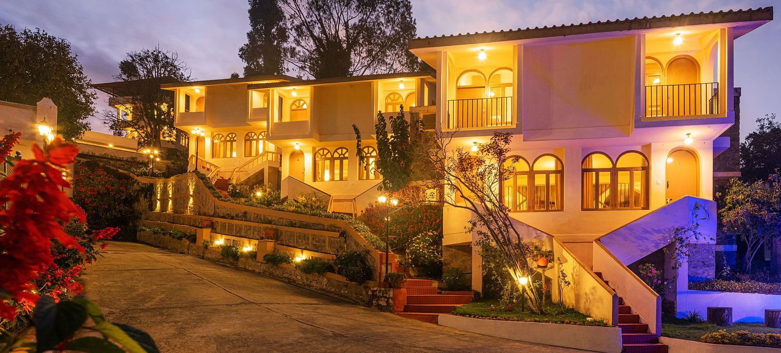 Resort entrance illuminated at night with warm lights, featuring a multi-story building and surrounding garden.