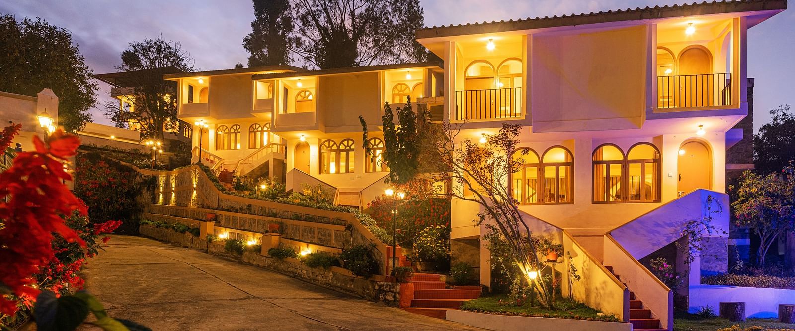 Resort entrance illuminated at night with warm lights, featuring a multi-story building and surrounding garden.