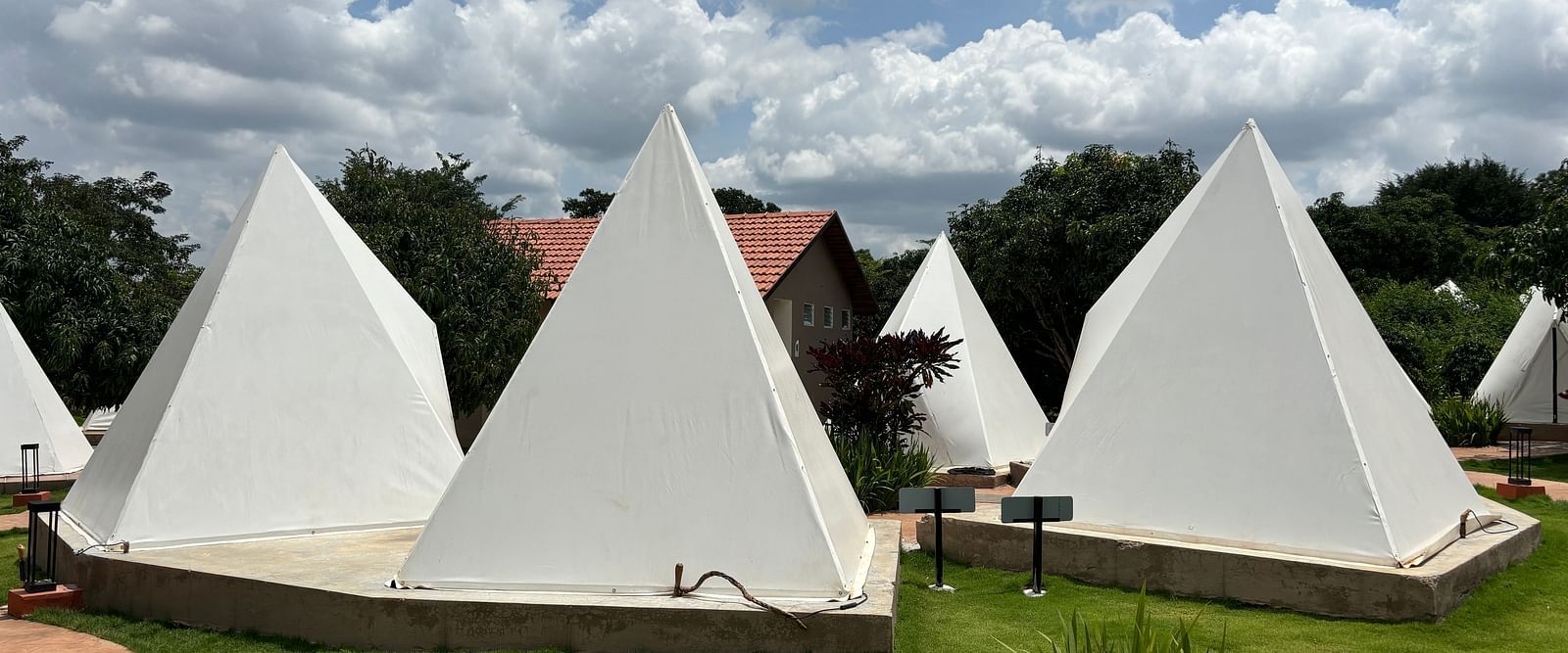 A scenic view of a resort area with tents lined along a neat walkway, surrounded by a well-maintained lawn.