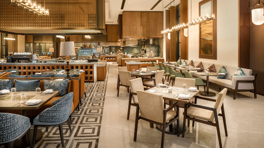 Dining seating area under warm pendant lighting at Chithirai restaurant, The Residency Signature Madurai, featuring banquette and wicker chairs