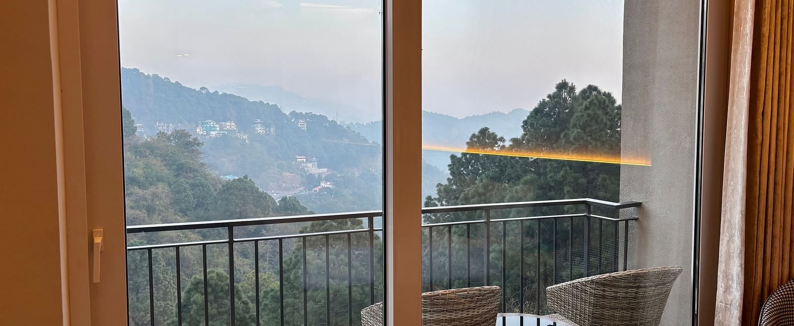 Balcony view with chairs and a table overlooking scenic hills and greenery at ARNISA Boutique Hotel