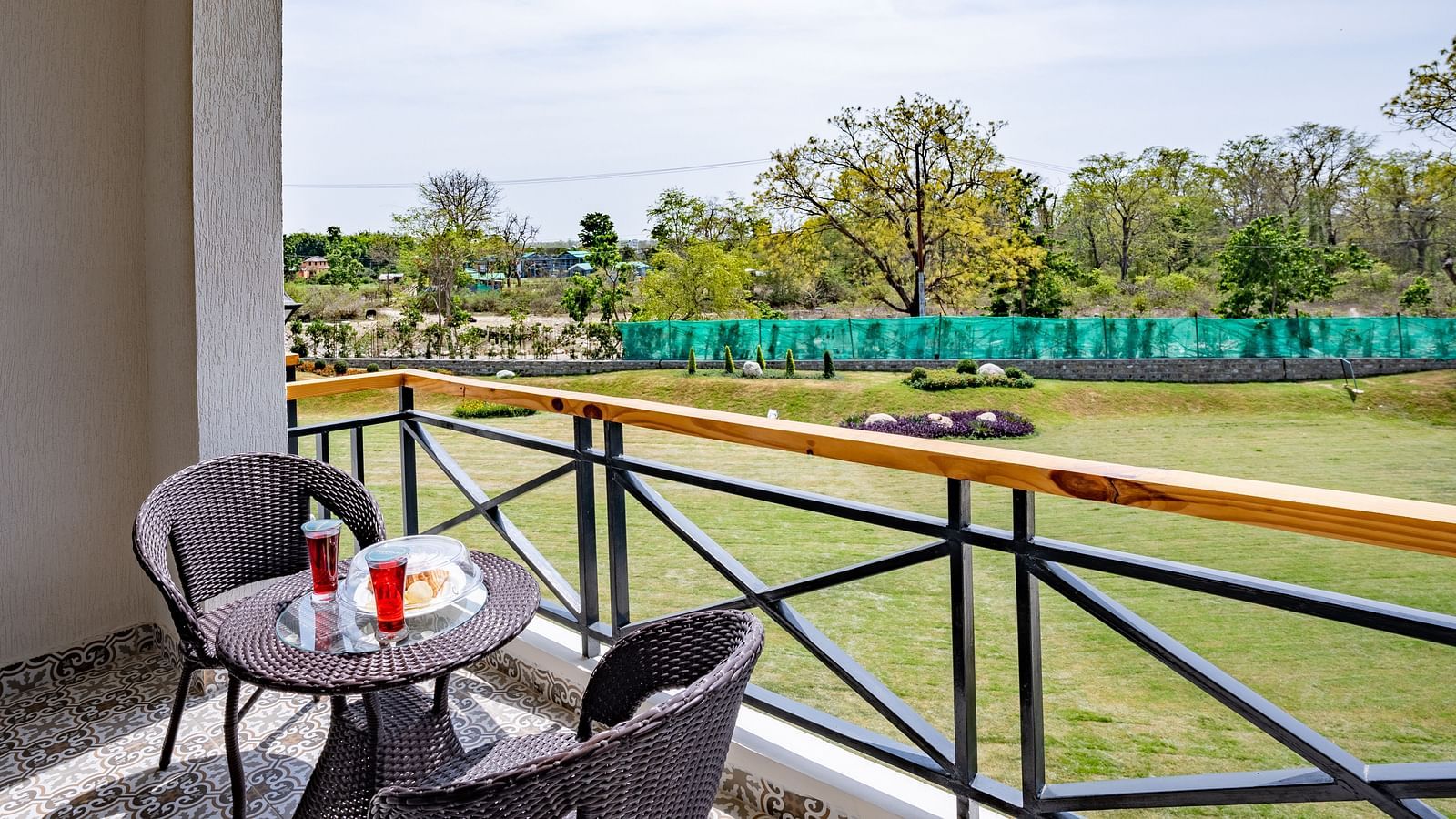 A balcony in the river view room with comfortable chairs placed around a coffee table for relxation - Shervani Pebbles & Pines, Corbett