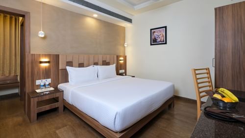 Deluxe Room at Pride Biznotel in Sasan Gir featuring a plush bed with two lamps lit over the nightstands on both sides