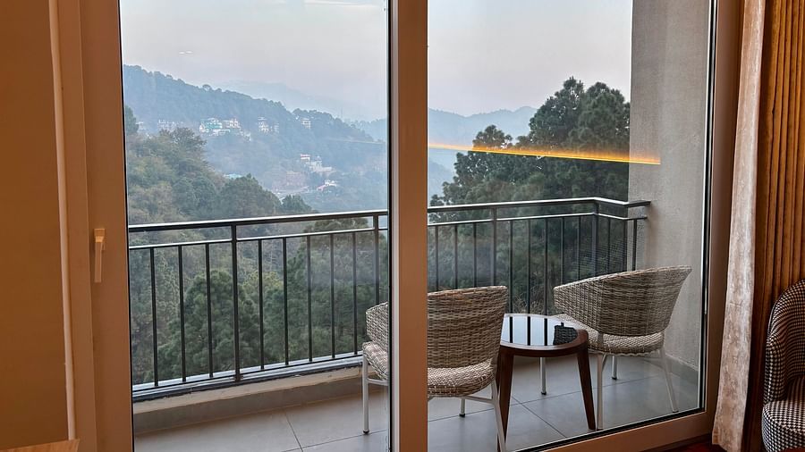 Balcony view with chairs and a table overlooking scenic hills and greenery at ARNISA Boutique Hotel