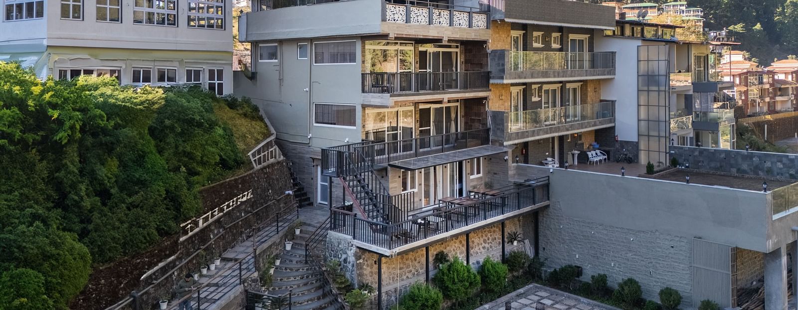 Exterior view of the hotel building with surrounding greenery and hillside landscape in the background.