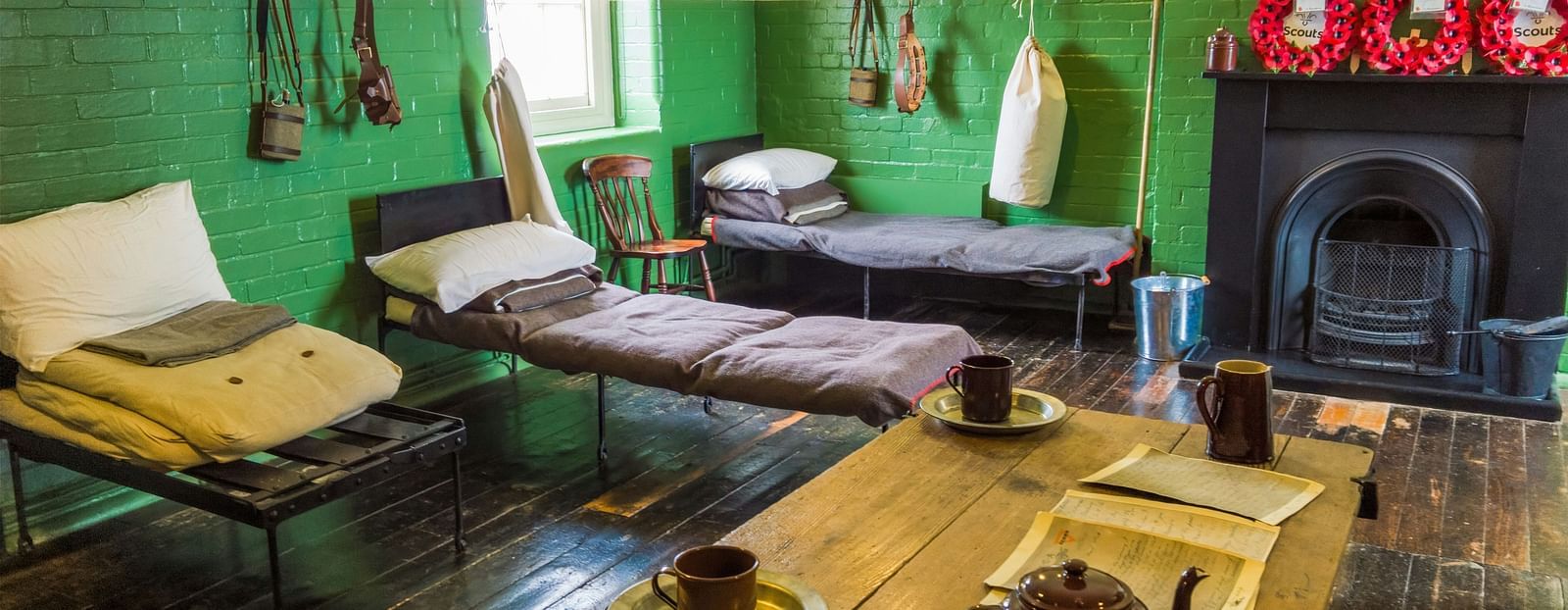 A dormitory room with comfortable beds, a desk and a fire place