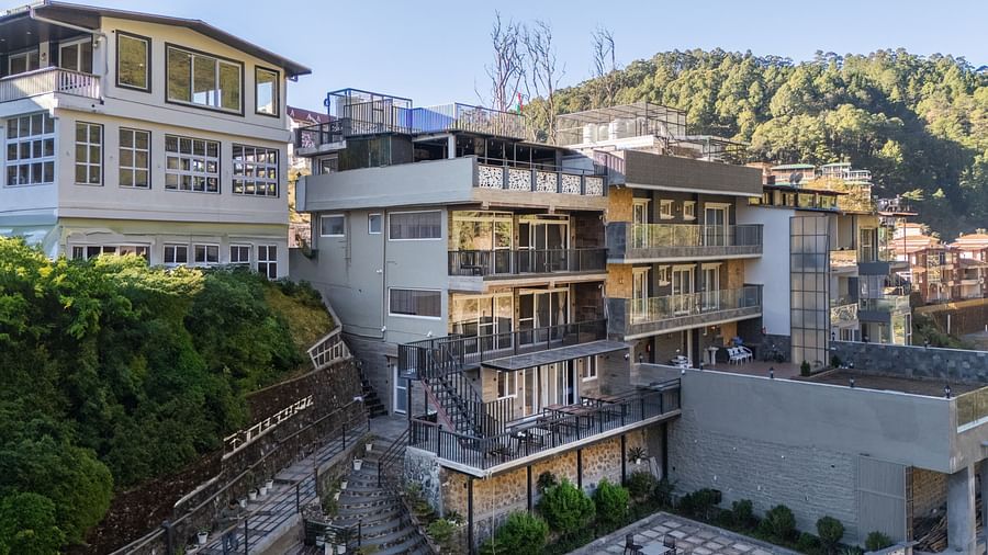 Exterior view of the hotel building with surrounding greenery and hillside landscape in the background.